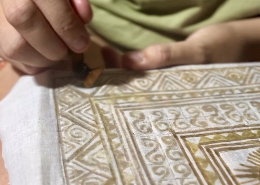 Vietnam 9 A close up of a piece of canvas with wax designs on it. A woman is using a tool to make the designs as part of a handcraft workshop with the Hmong in Sapa, Vietnam.
