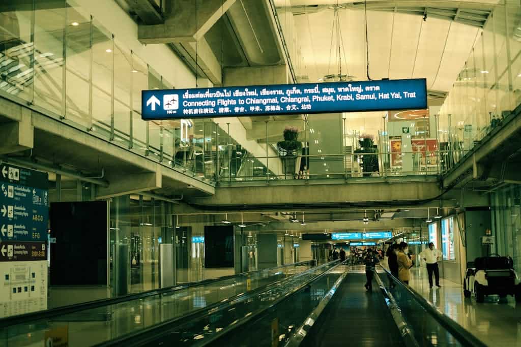 BEST Food in Chinatown Bangkok: What is Actually Worth It 16 View of Suvarnabhumi Airport interior with moving walkway and signs for connecting flights.