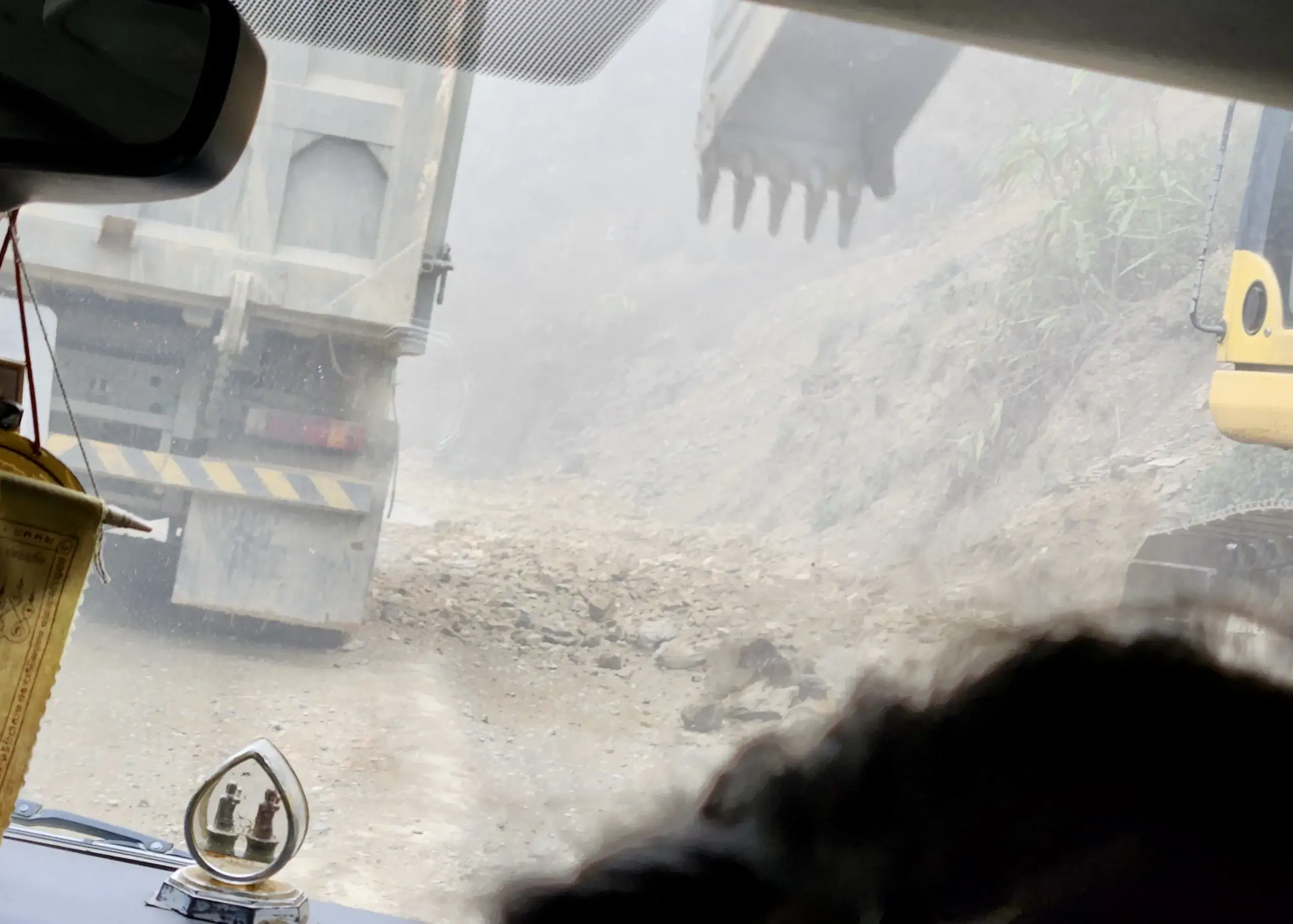 Motorbiking in Laos: Routes, Rentals, Costs & Safety Tips 7 A view from the window of a bus in Laos. Outside there is a digger transporting dirt from the roads after a landslide