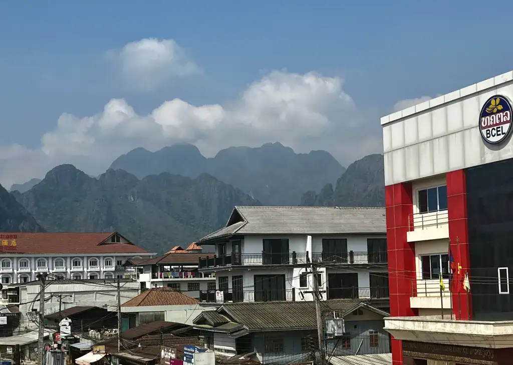 The picture shows the BCEL bank building in Laos with beautiful mountains in the background
