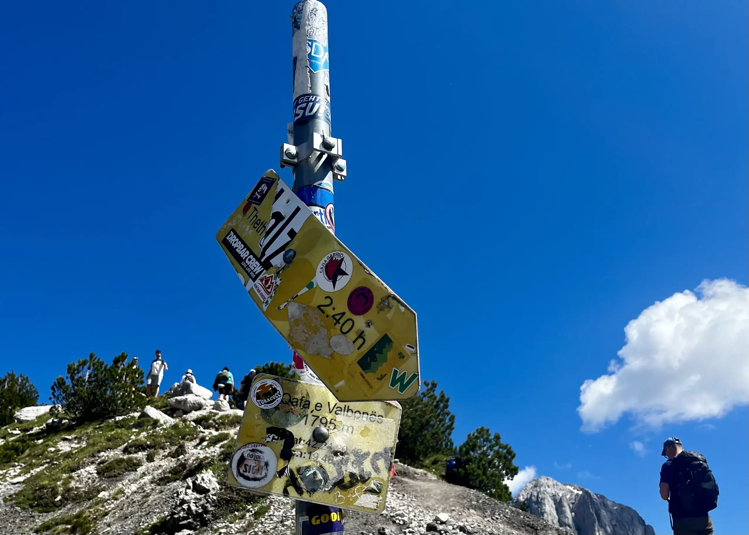A yellow sign showing distances to Theth and Valbona, at the top of the Valbona Pass summit