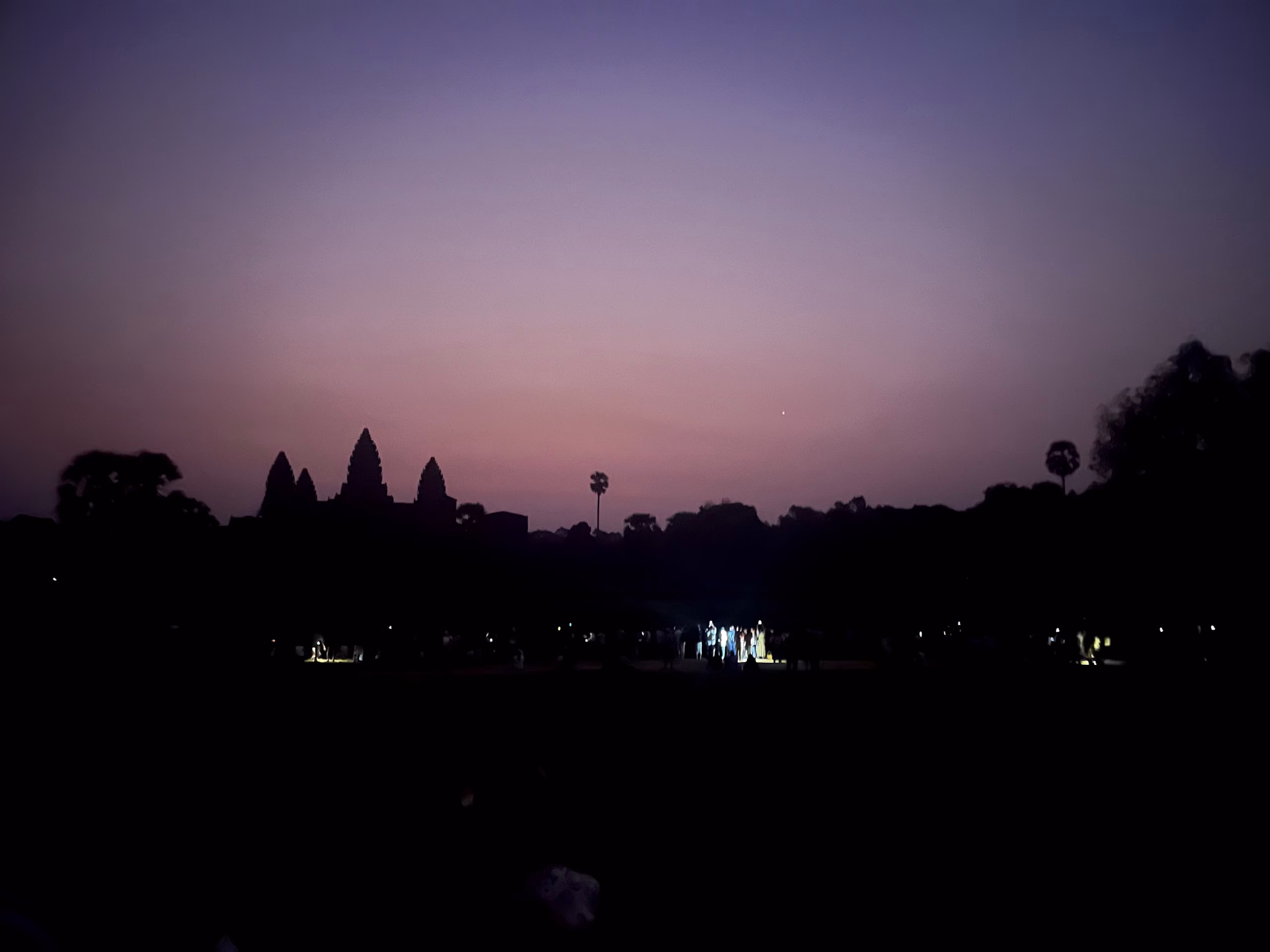 Best Angkor Wat Tour for Sunrise - Our Top Picks 2 The purple sunrise is glowing above the outline of angkor wat.