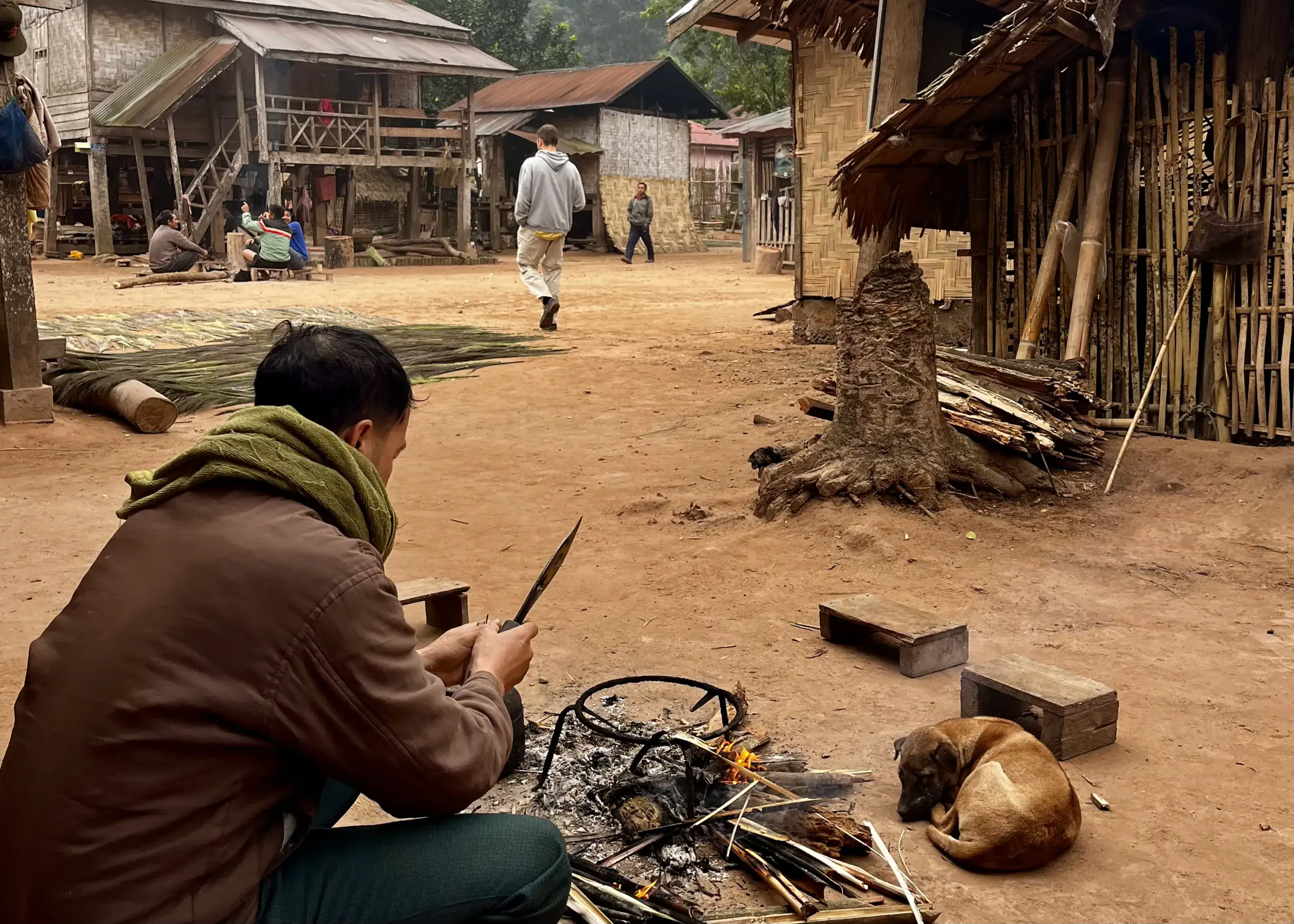 The Best Homestay in Sapa: A Beginner’s Guide to Homestays 6 A man in a brown jacket is cooking bamboo over a fire in a jungle village at a homestay in Northern Laos.
