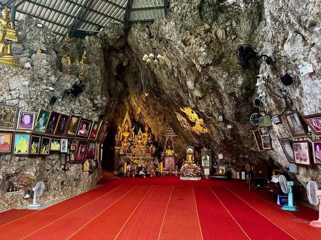 Where to Stay in Chiang Dao: 3 Best Areas & Top Picks 5 The pciture shows the inside of a large cave. The floor has been lined with red carpet and the cave walls are filled with buddhist symbols