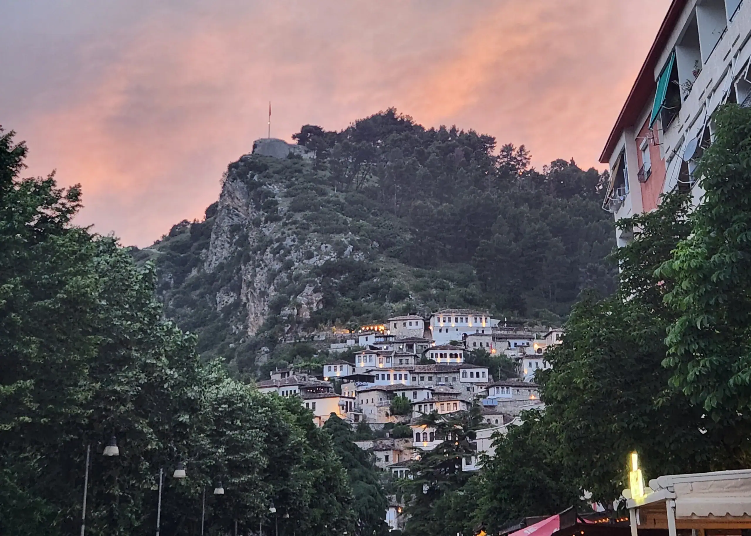 A street in Berat - a must stop in an Albania itinerary. The houses are stacked on top of each other in the distance and the sky is orange from the sunset
