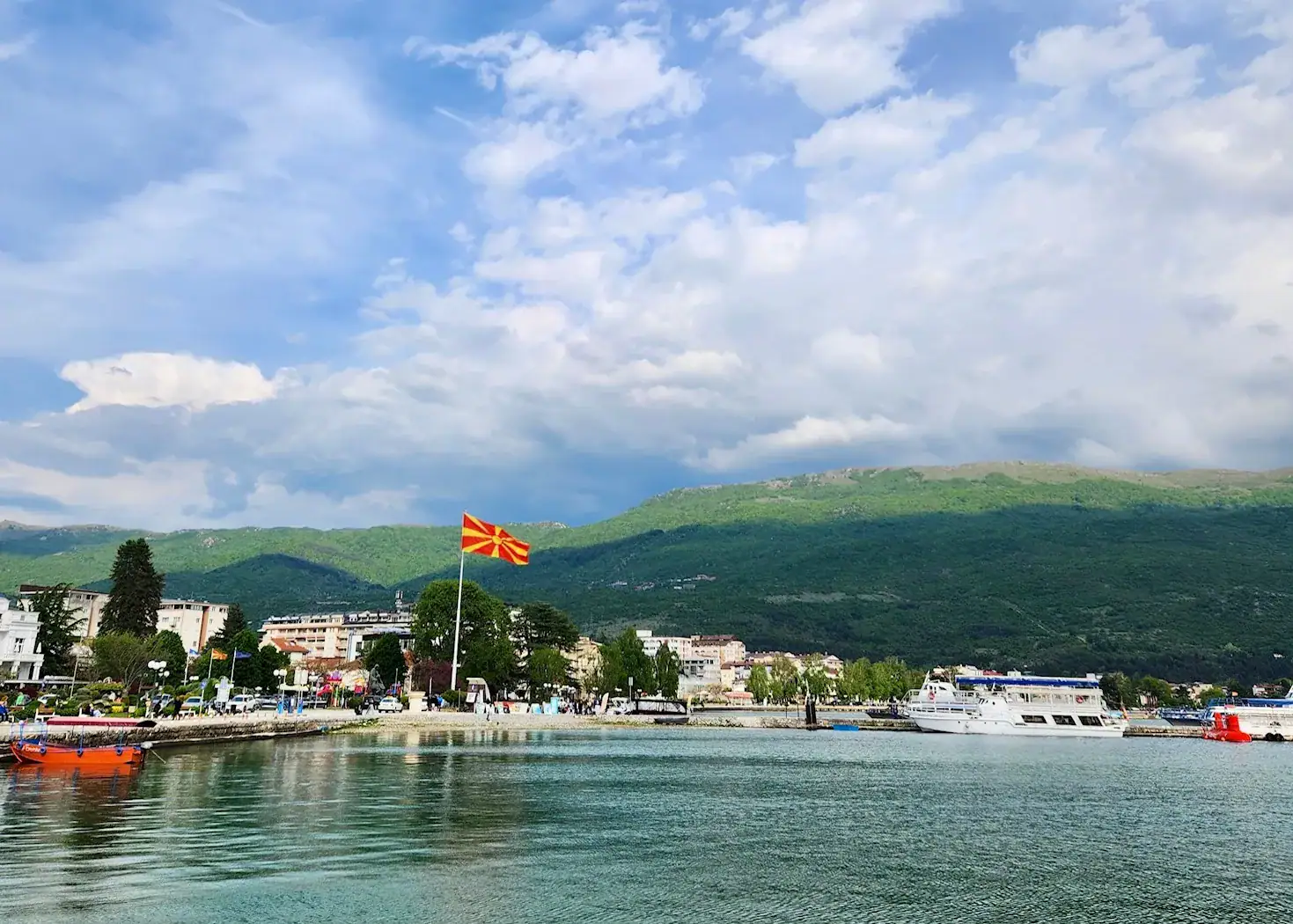 9 Exciting Things To Do in Ohrid, North Macedonia 1 A picture of Lake Ohrid taken from the shore. There is a Macedonia flag flying high above the buildings