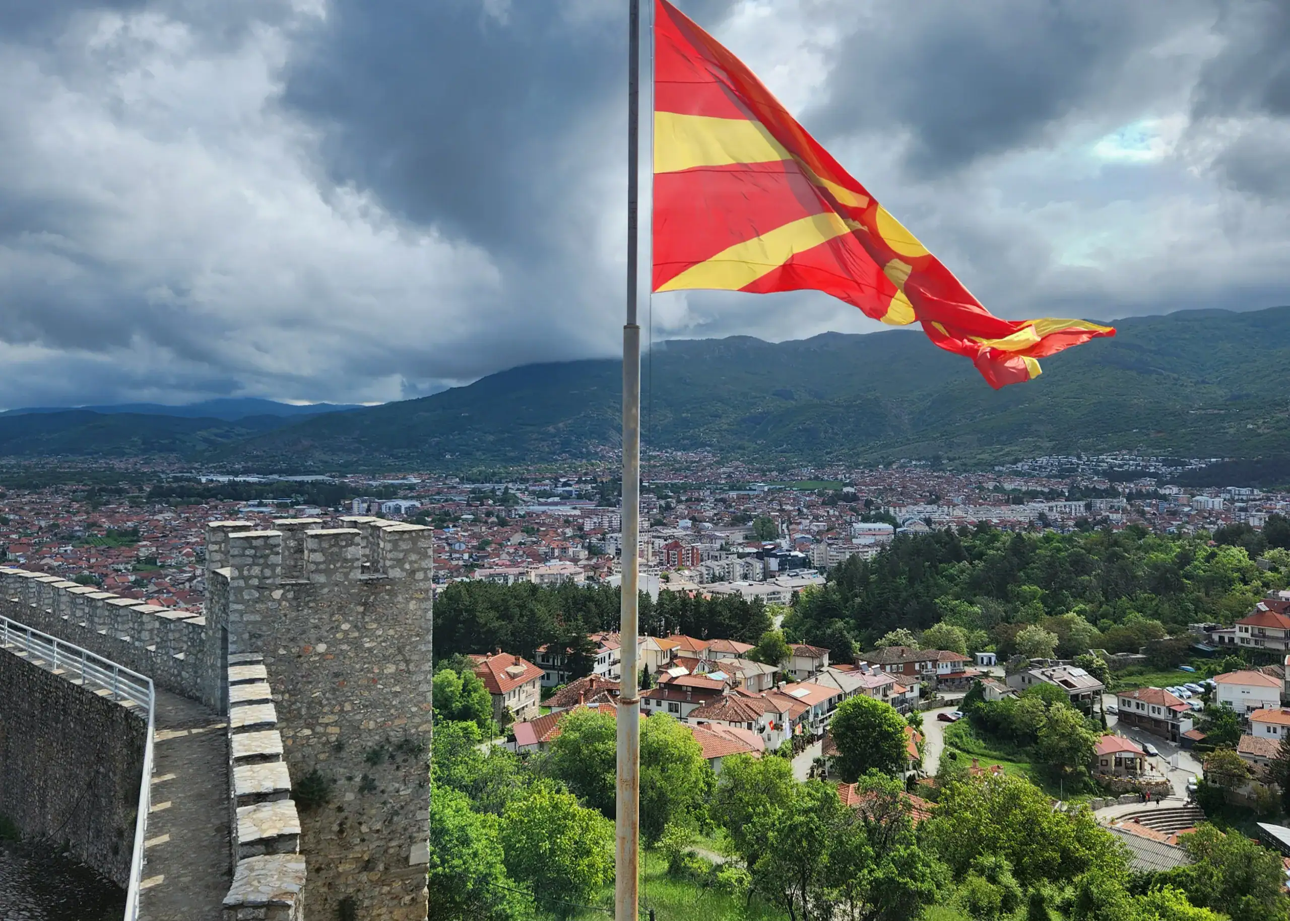 9 Exciting Things To Do in Ohrid, North Macedonia 4 A stone castle meanders around the city of houses with orange rooves. In the foreground, there is the red and yellow Macedonia flag flying high