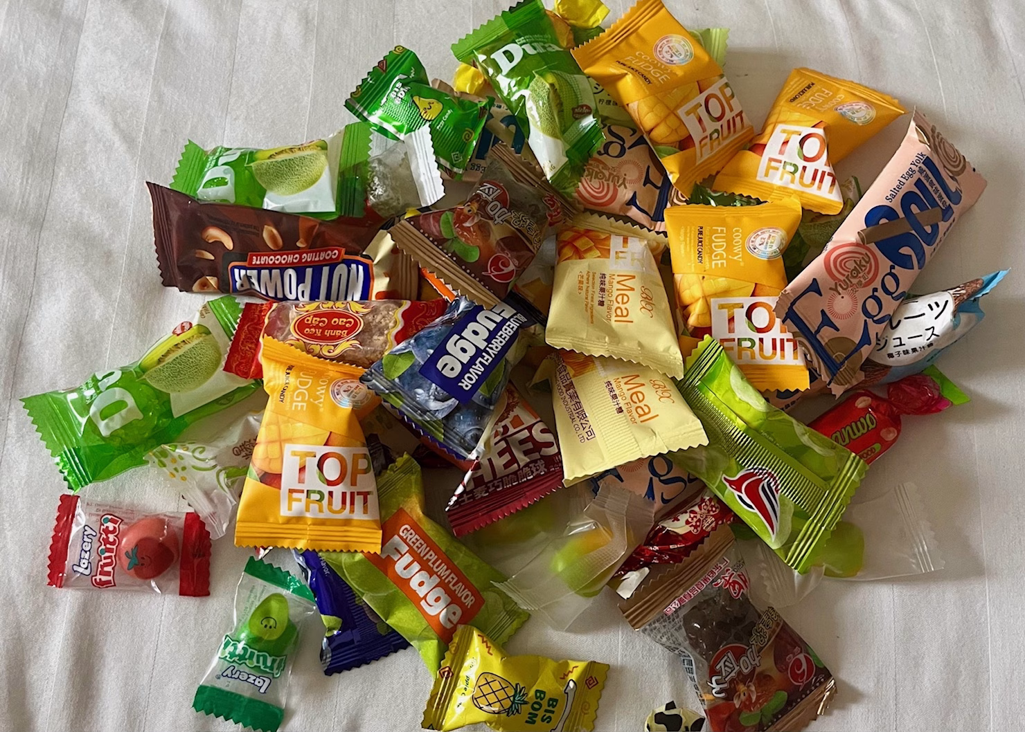 Food in Hanoi: The Best Old Quarter Restaurants 8 A pile of Vietnamese candy is sitting on a bed with a white sheet. They are all small gummies and hard candies in different flavors and colors bought by weight from a street vendor.