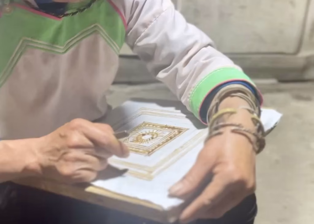 Laos or Vietnam: How to Choose the Best Country for Your Trip 17 The Hmong host of a handicraft workshop is demonstrating how to create traditional designs in wax. She is wearing traditional Hmong clothing with bright green and pink details as well as many gold bracelets.