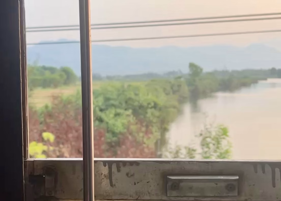 Bangkok to Chiang Mai Travel Guide — How to Get There by Train, Bus & Plane 1 The view of distant hills and a river out the rusty window of a train heading to Ho Chi Minh City from Da Nang. This was taken on an overnight sleeper train from Bangkok to Chiang Mai.