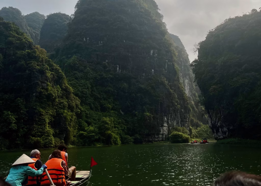 Tam Coc Bicycle Tour: The Perfect Self-Guided Route 8 A row boat is floating down the Trang An Scenic Landscape Area - one of the best things to see in Ninh Binh.