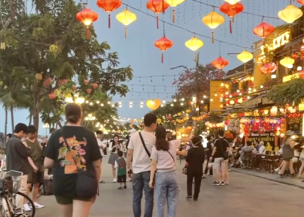 Laos or Vietnam: How to Choose the Best Country for Your Trip 30 A busy street in Hoi An at dusk with people walking down and string lanterns in yellow and red swinging overhead
