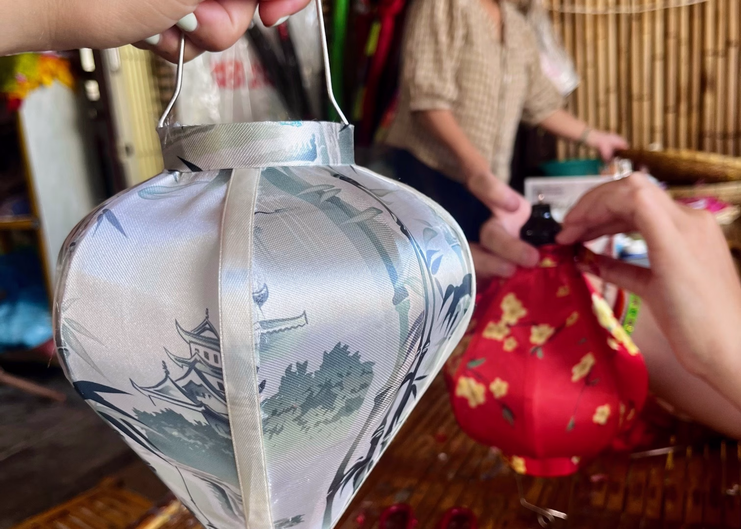 Hoi An Itinerary: 3 Days of Food & Lantern-Lit Charm 3 Two people making handmade lanterns at a class in Hoi An. They are attaching fabric to a wooden lantern structure