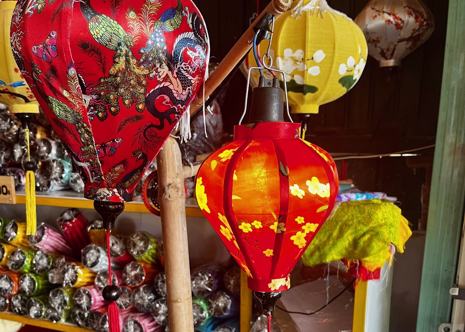 4 Week Vietnam Itinerary: Laid-Back Adventures on a Budget 8 There are three lanterns, two red and one yellow, at a stall in Hoi An. There are lots of lanterns in different patterns in the background