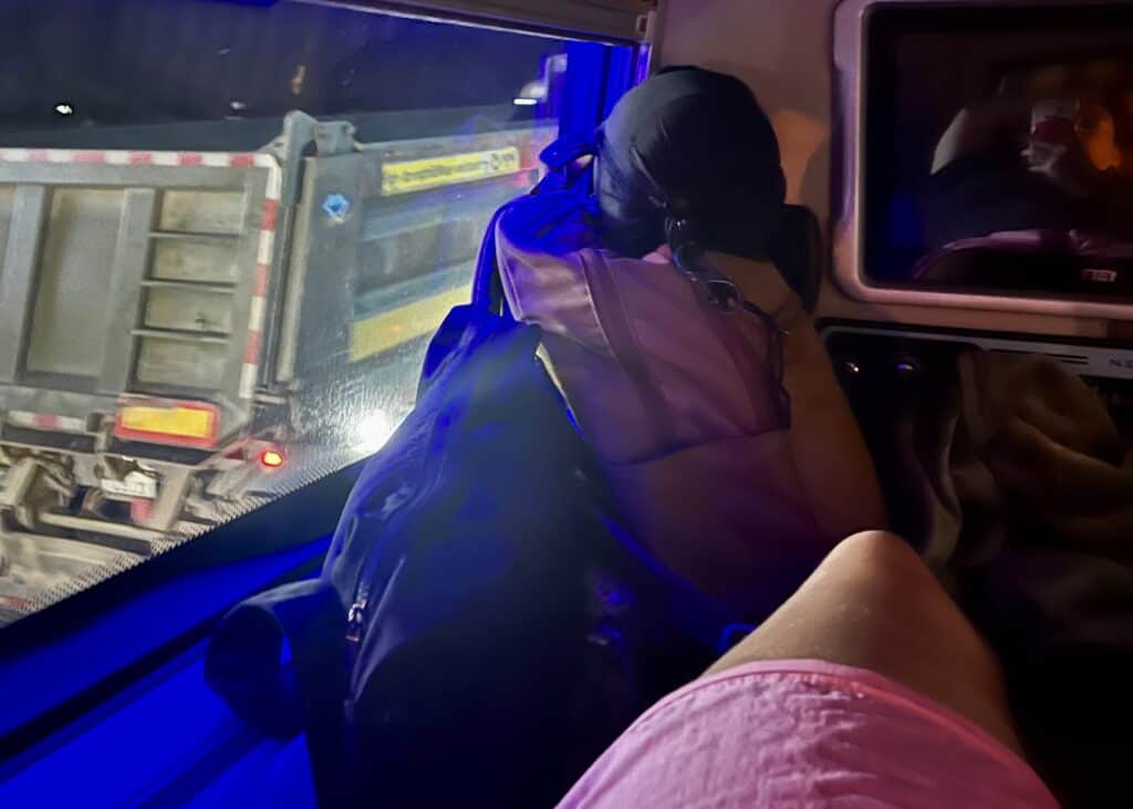Laos or Vietnam: How to Choose the Best Country for Your Trip 23 A woman's legs are extended out on a top bunk on a sleeper bus in Vietnam. Her day bag with her valuables in it is next to the window beside her for safe keeping.