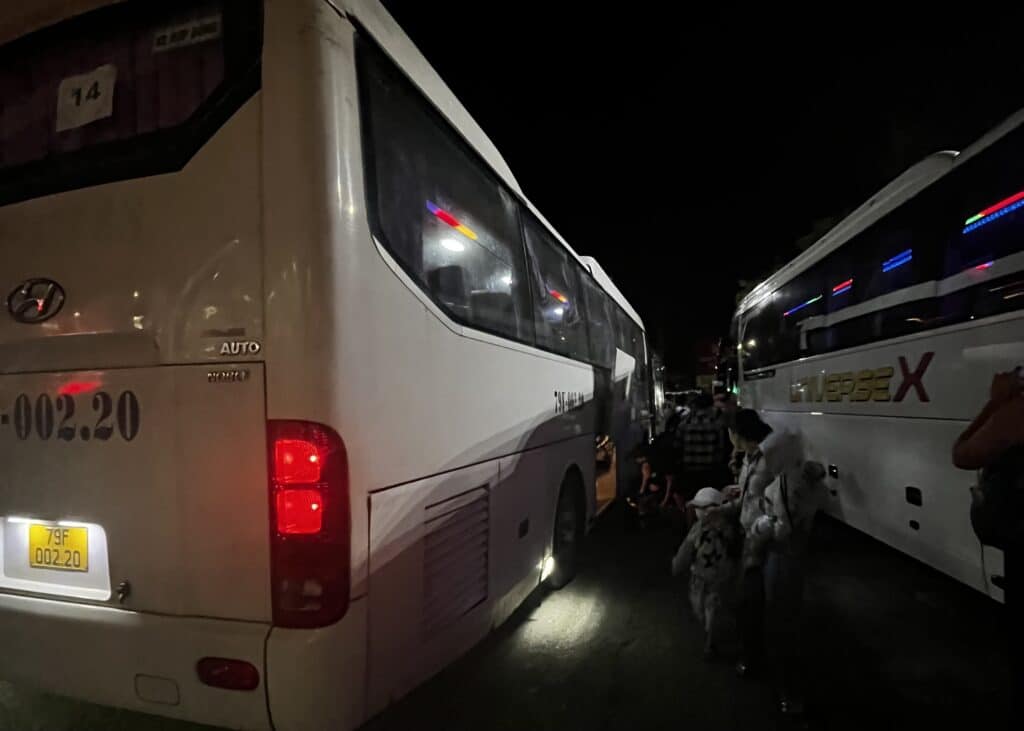 Bangkok to Chiang Mai Travel Guide — How to Get There by Train, Bus & Plane 9 Two buses in the dark in Vietnam. People are loading their luggage into the bottom of the bus.