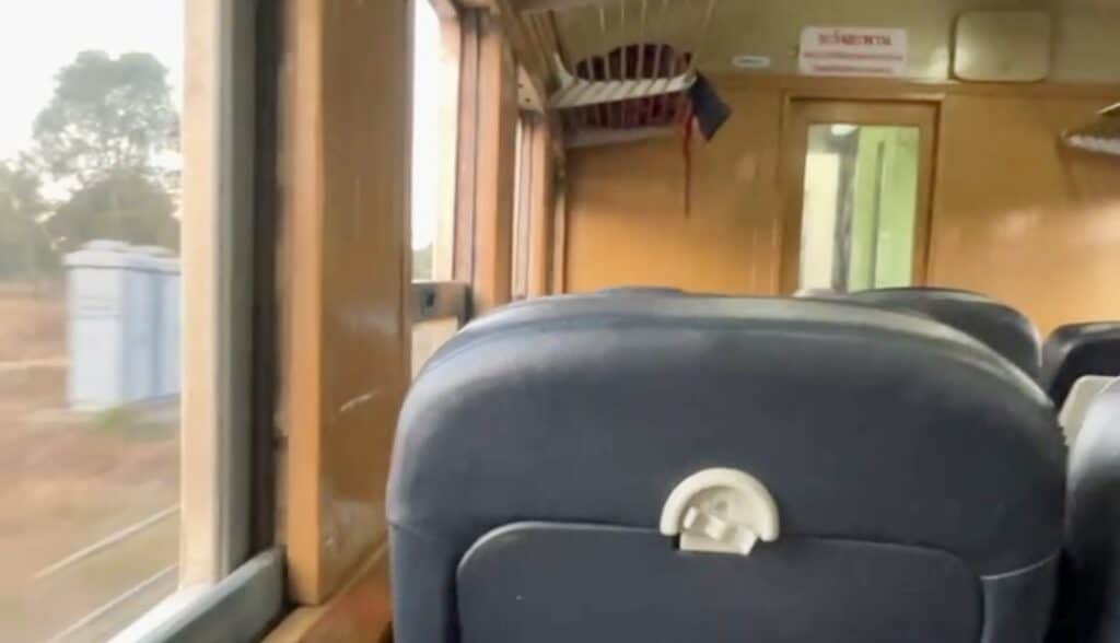 Bangkok to Chiang Mai Travel Guide — How to Get There by Train, Bus & Plane 4 A blue leather seat on a train is in the foreground surrounded by the wooden inside of a sleeper train in Vietnam.