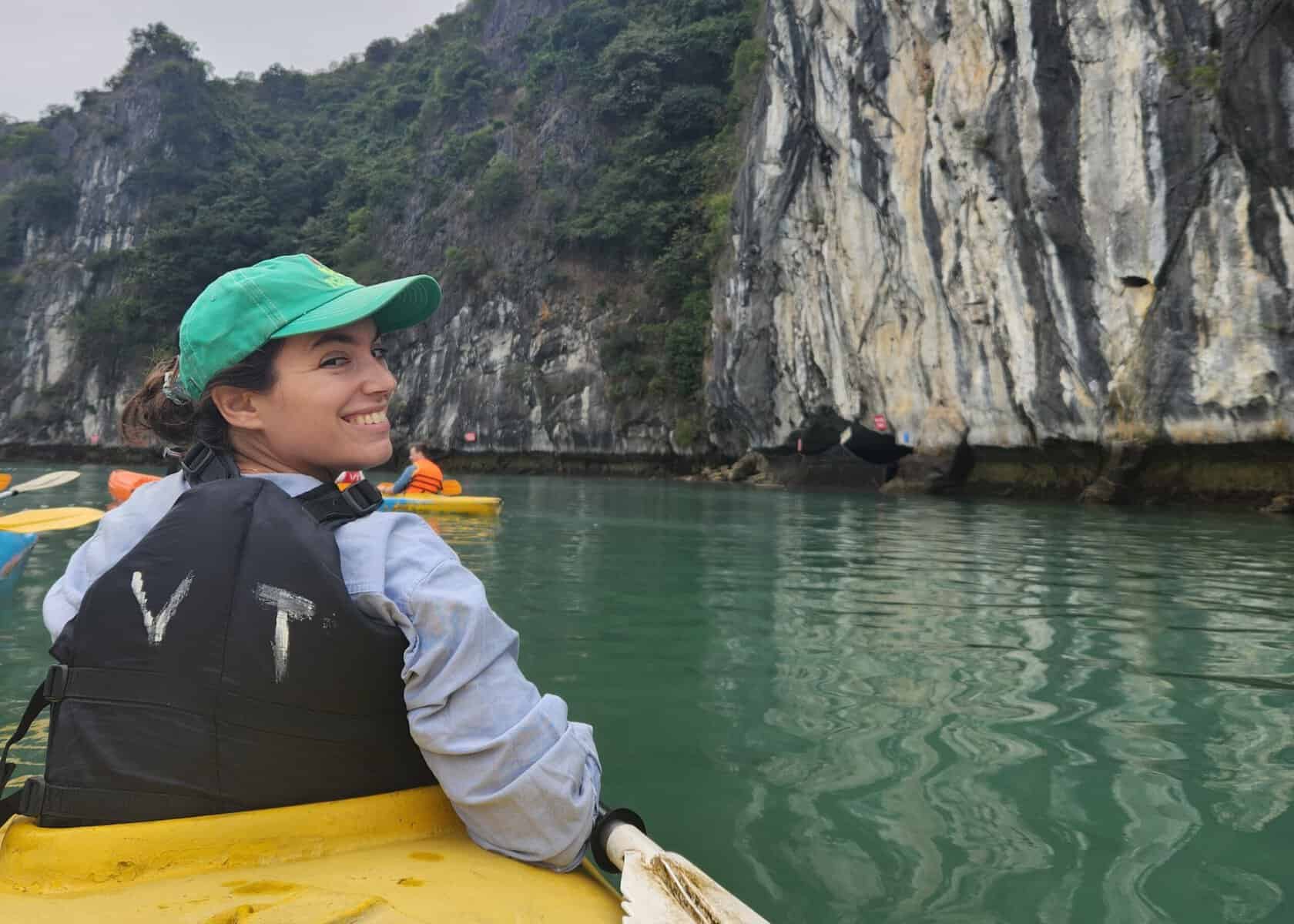 7 Best Places to Go in Vietnam (And What They’re Really Best For) 10 A woman in a yellow kayak is turning around and smiling. Shes on the water, surrounded by the mountains in Halong Bay.