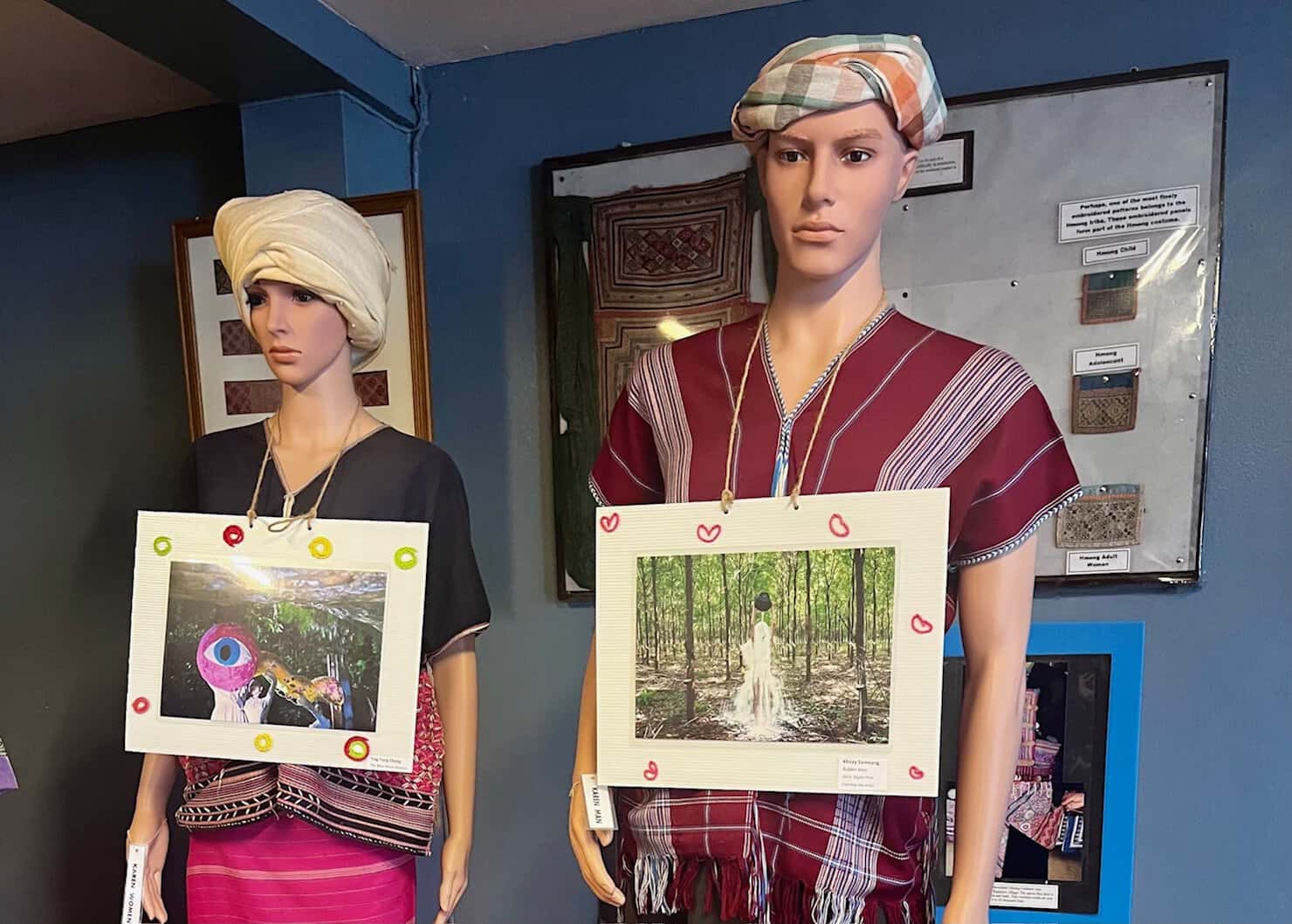 two figures dressed in Northern Thailand hilltribe attire are at the Chiang Rai Hilltribe Museum.
