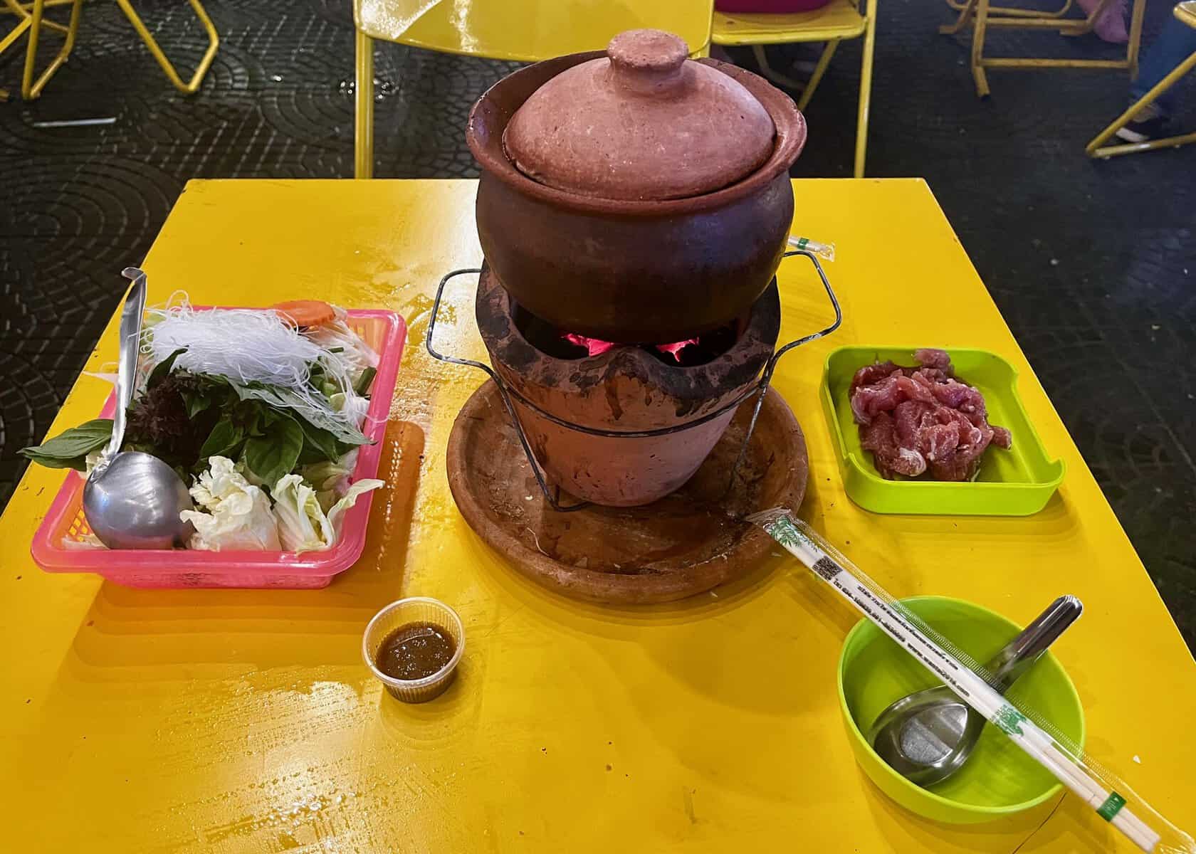 An order of hotpot sits on a yellow table at the Chiang Rai night bazaar.