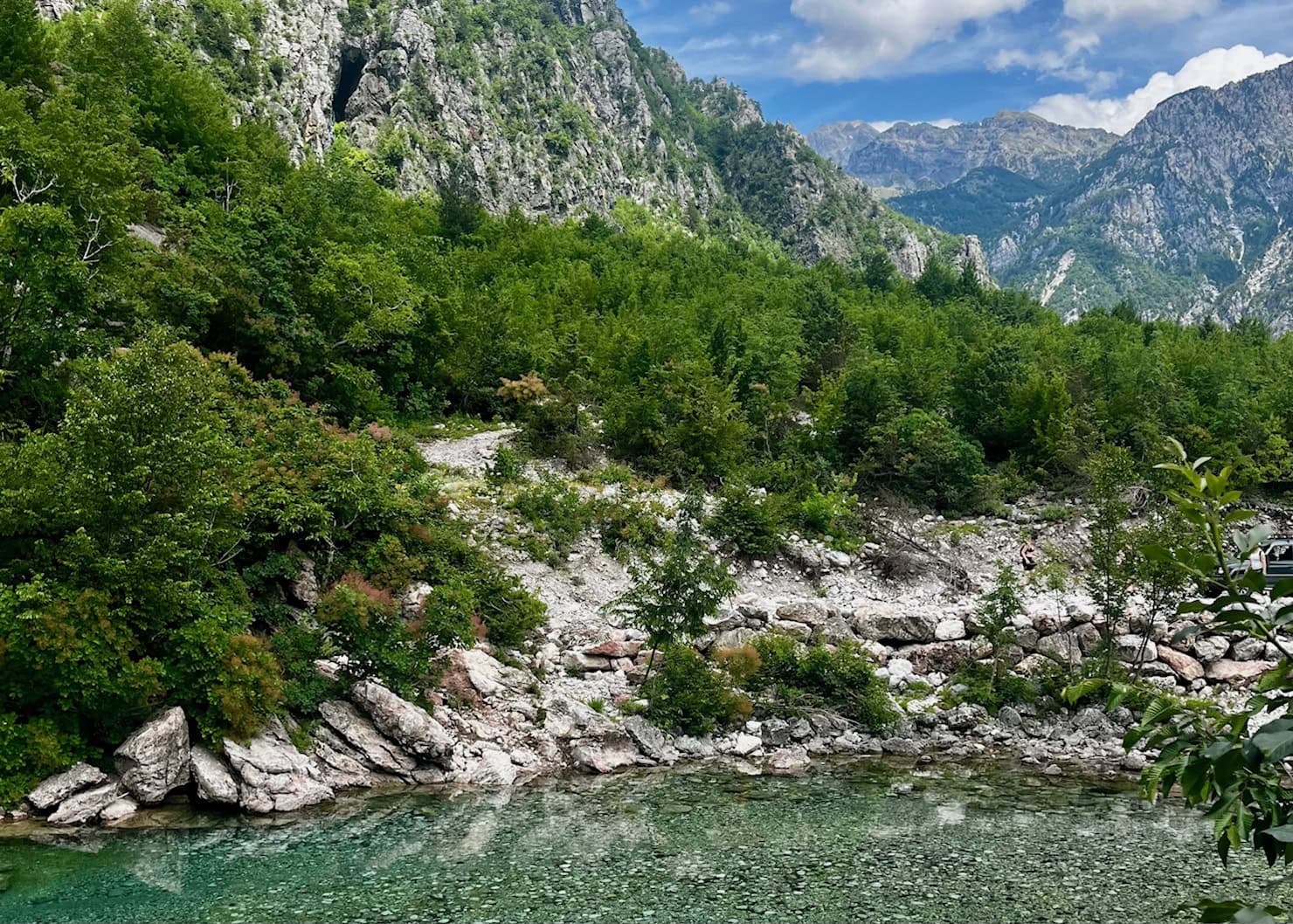 Where to Stay in Theth: Best Value Guesthouses 9 A clear river flows beneath the white rocky mountains surrounding Theth, Albania.