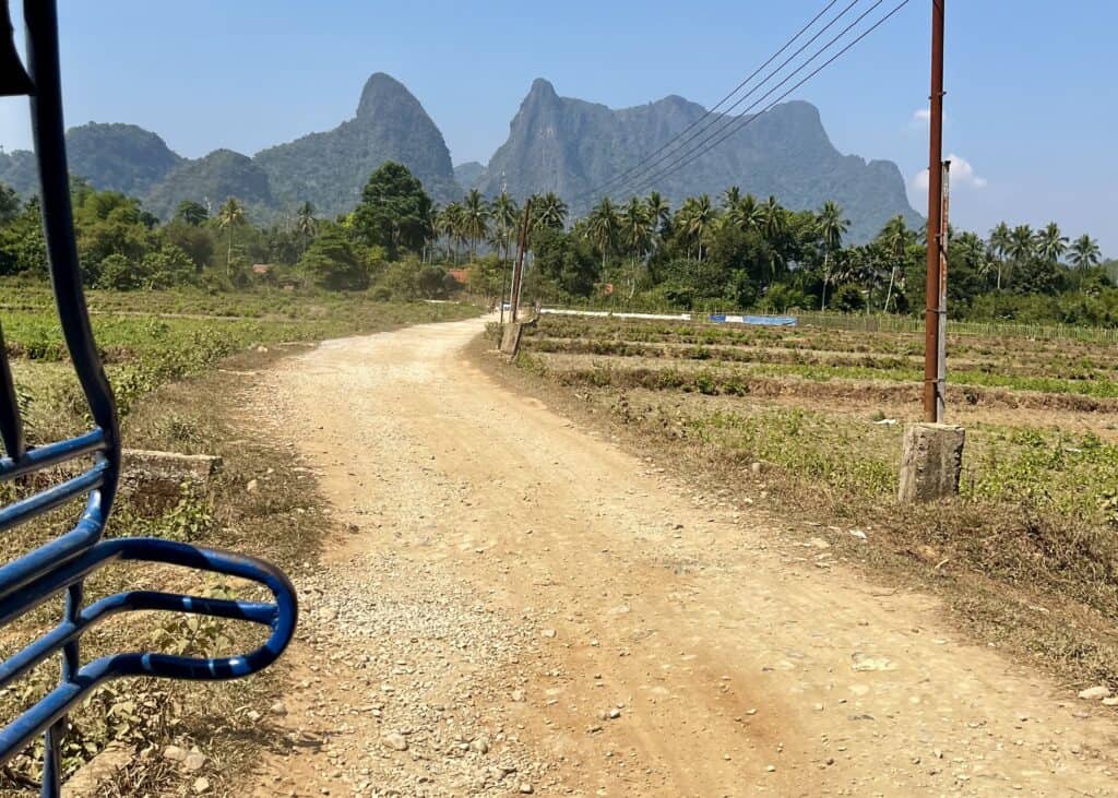 A dusty road seen from the back of a tuktuk in Vang Vieng Laos.