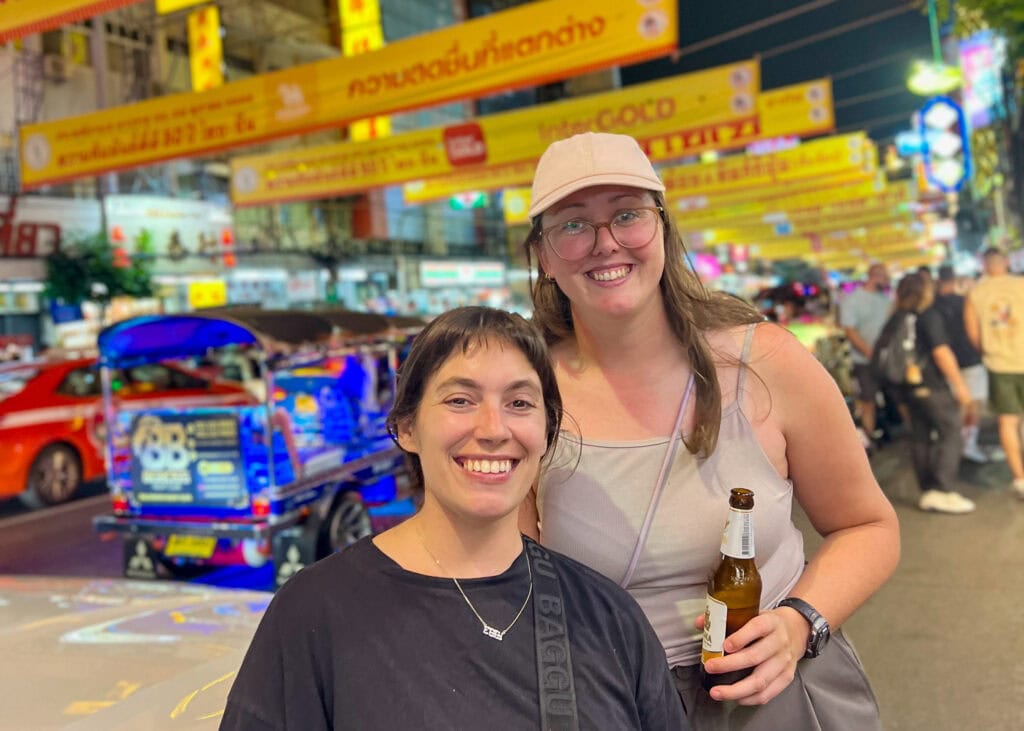 Bangkok Food Tour: Our Honest Review of Chinatown’s Best Street Eats 17 Two women are posing and smiling in front of the lights at the Bangkok Chinatown night market