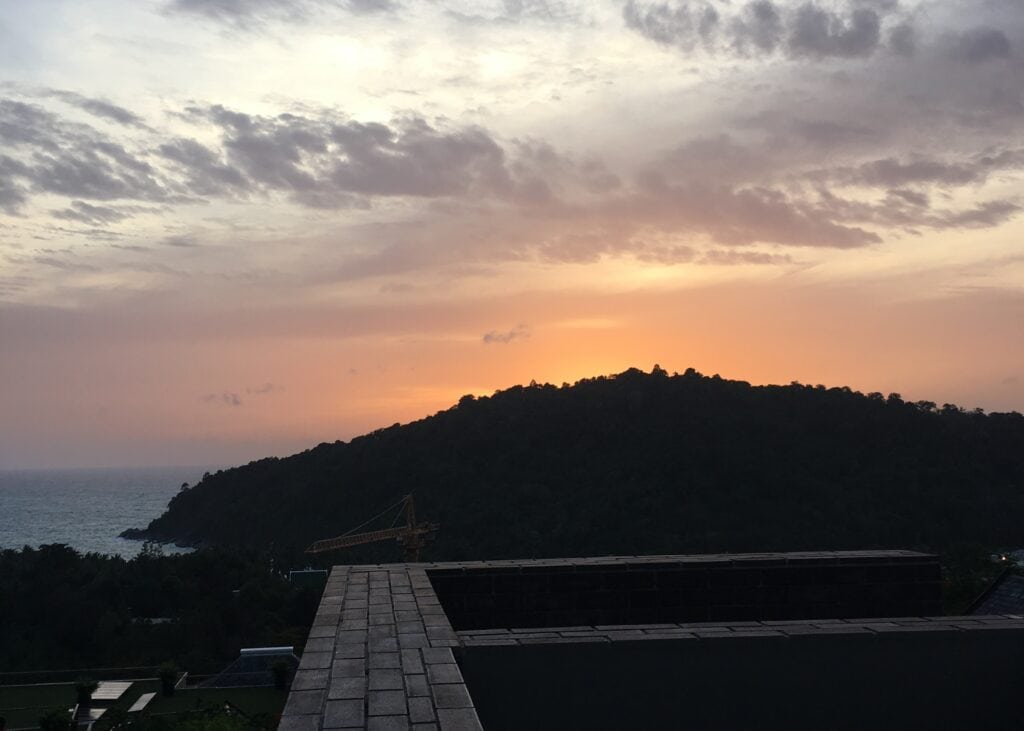 Phuket vs Krabi: Our 20s Party Trip vs 30s Chill Trip 5 The view from the restaurant at Avista Hideaway Resort in Phuket. From the table you can see over the ledge of the resort, to the ocean, with the sun setting behind the mountains