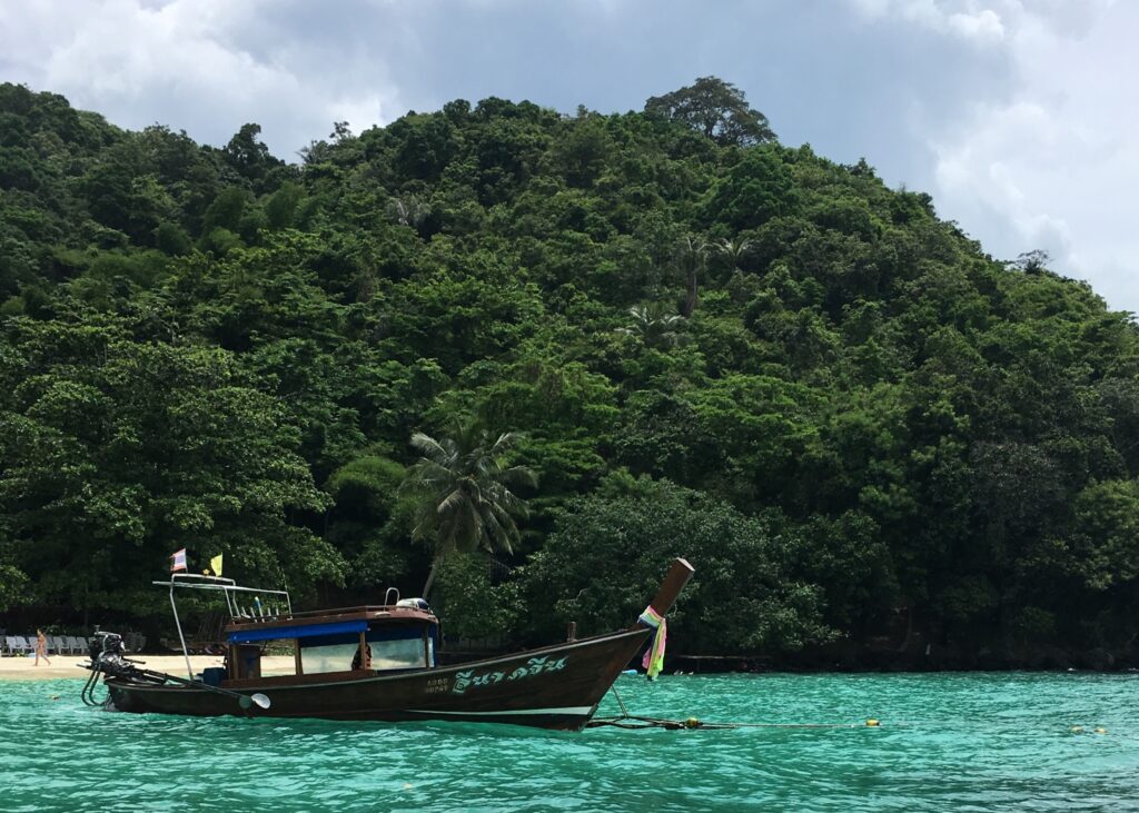 Phuket vs Krabi: Our 20s Party Trip vs 30s Chill Trip 6 A typical longboat in Thailand, sitting on the turquoise waters with vibrant green mountains in the backdrop