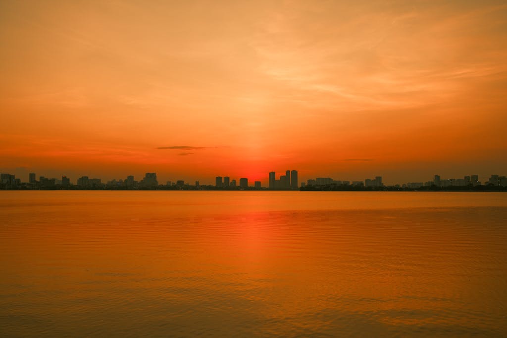Where to Stay in Hanoi: Best Neighborhoods + Our Favorite Hotels 4 A vivid sunset casts a golden hue over the serene waters ofWest Lake, Hanoi, Vietnam.